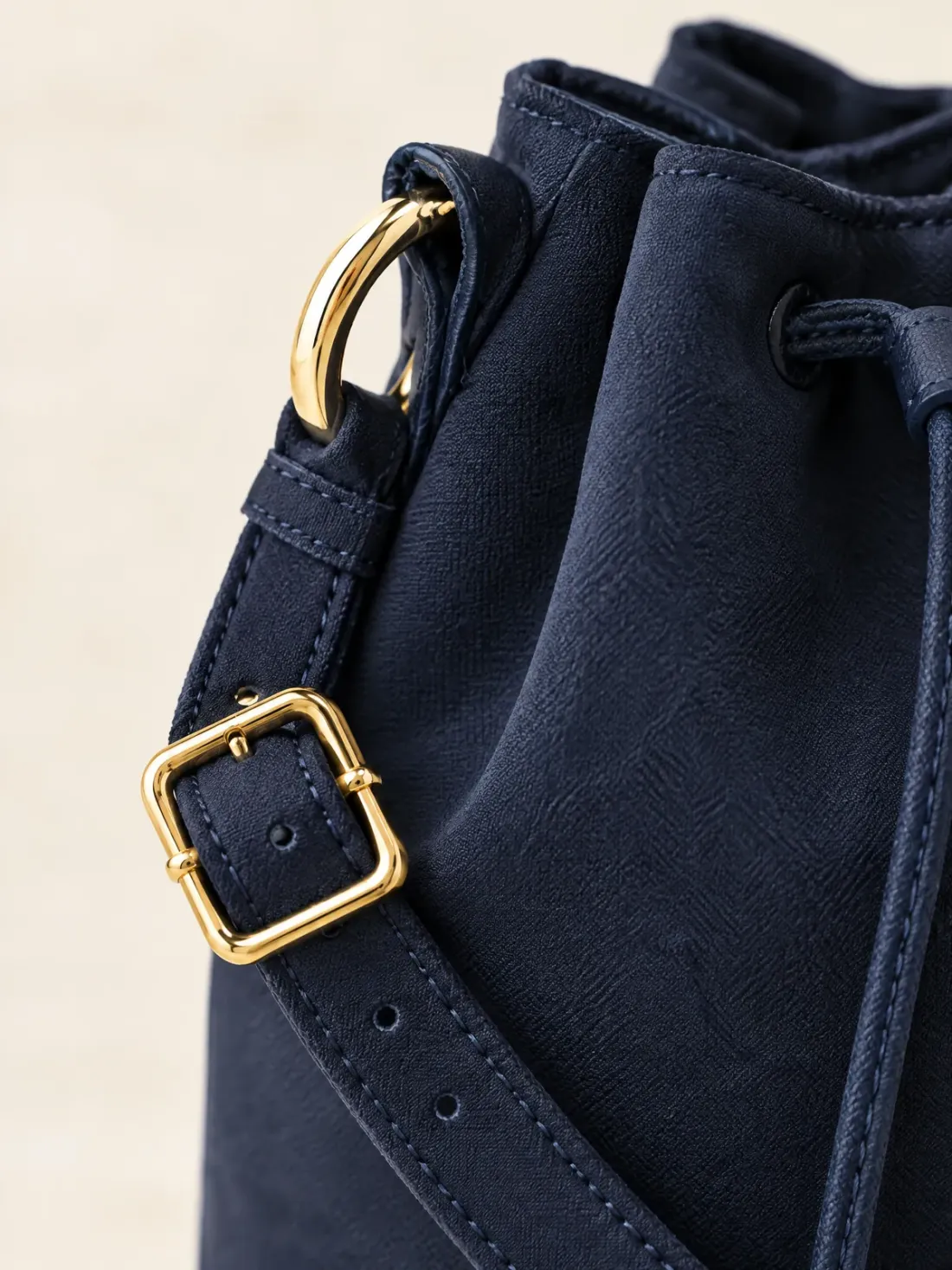 Crossbody Mini Bucket, close-up of the gold-tone buckle on the crossbody strap and the side ring
