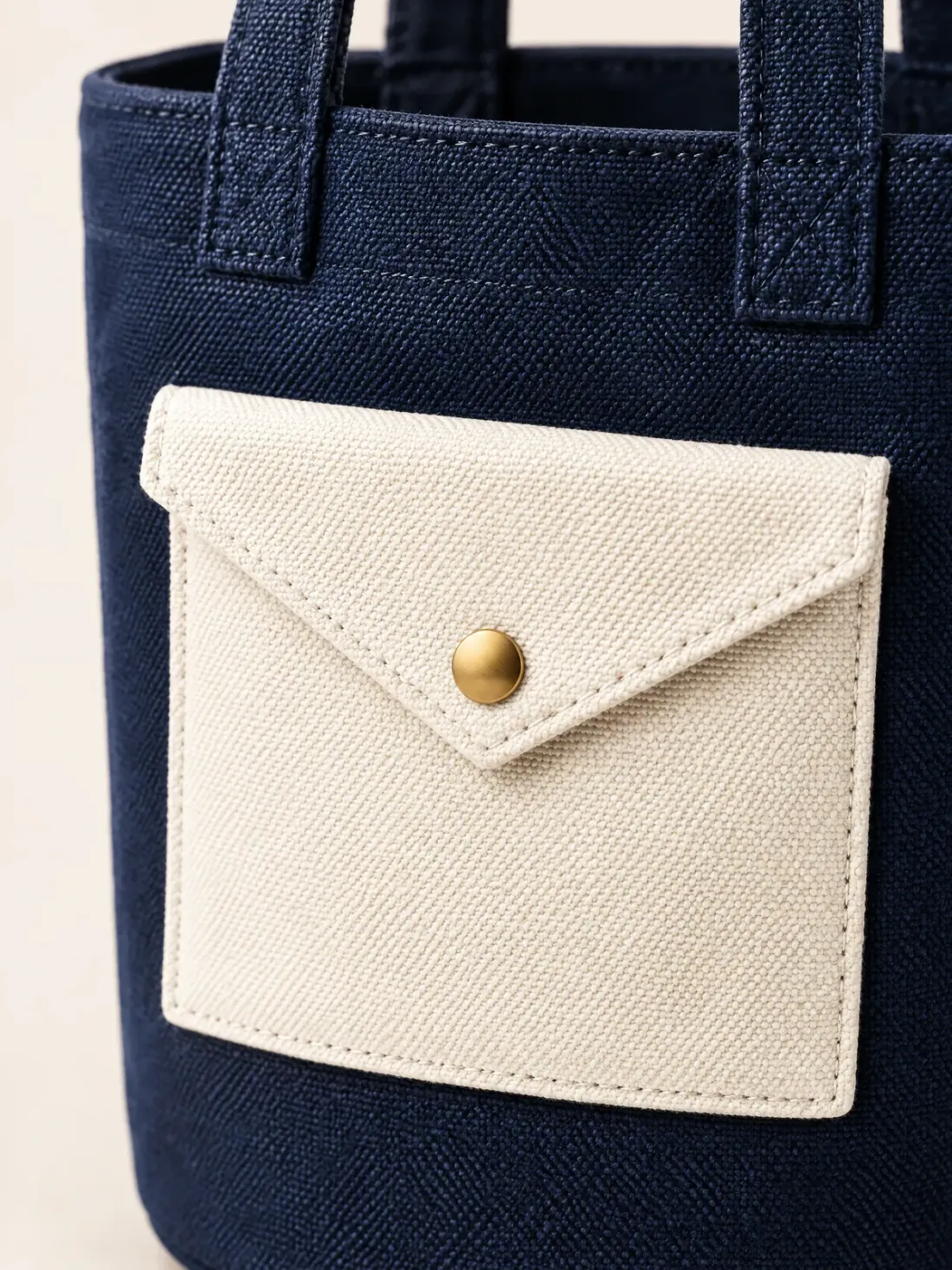 Letterbox Bucket Tote, close-up of the envelope-shaped front pocket with triangular flap and gold-tone button