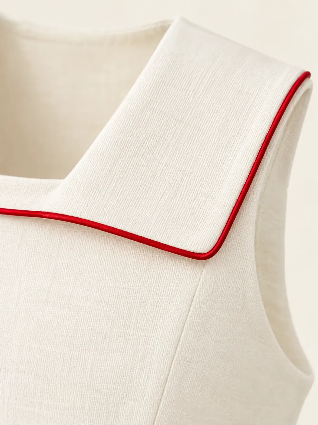 Postmark Sleeveless Collar Top, close-up of the single signal-red piping line tracing the collar edge at the back flap corner