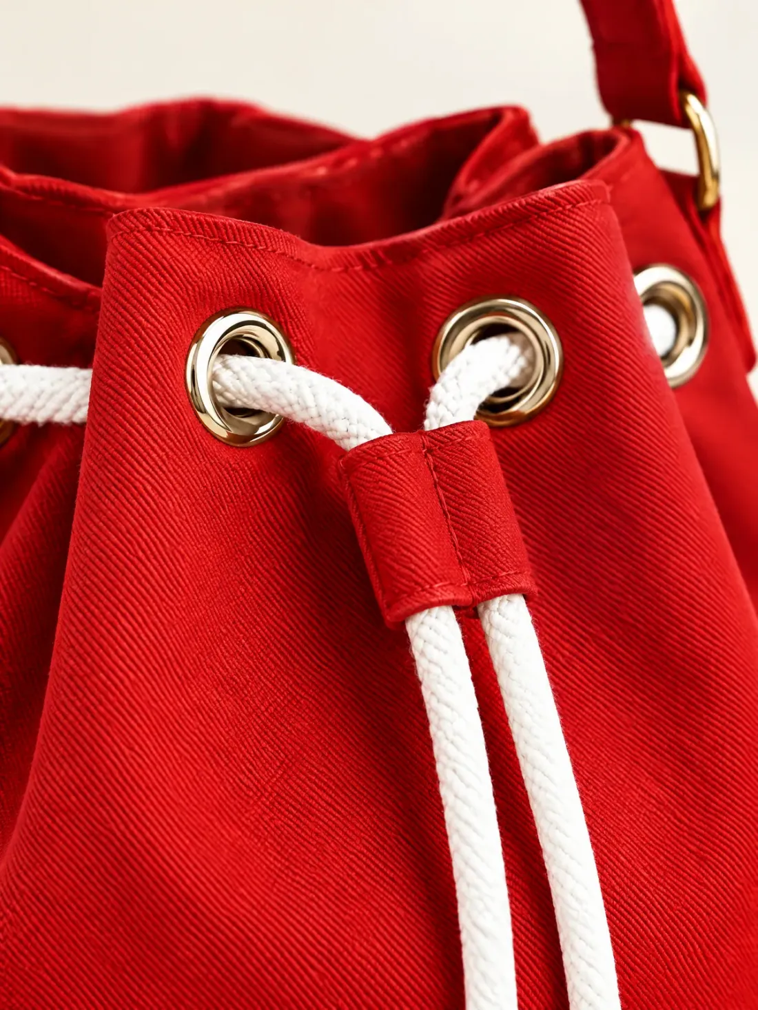 Signal Red Mini Bucket, close-up of the white cord through the gold-tone eyelets on red