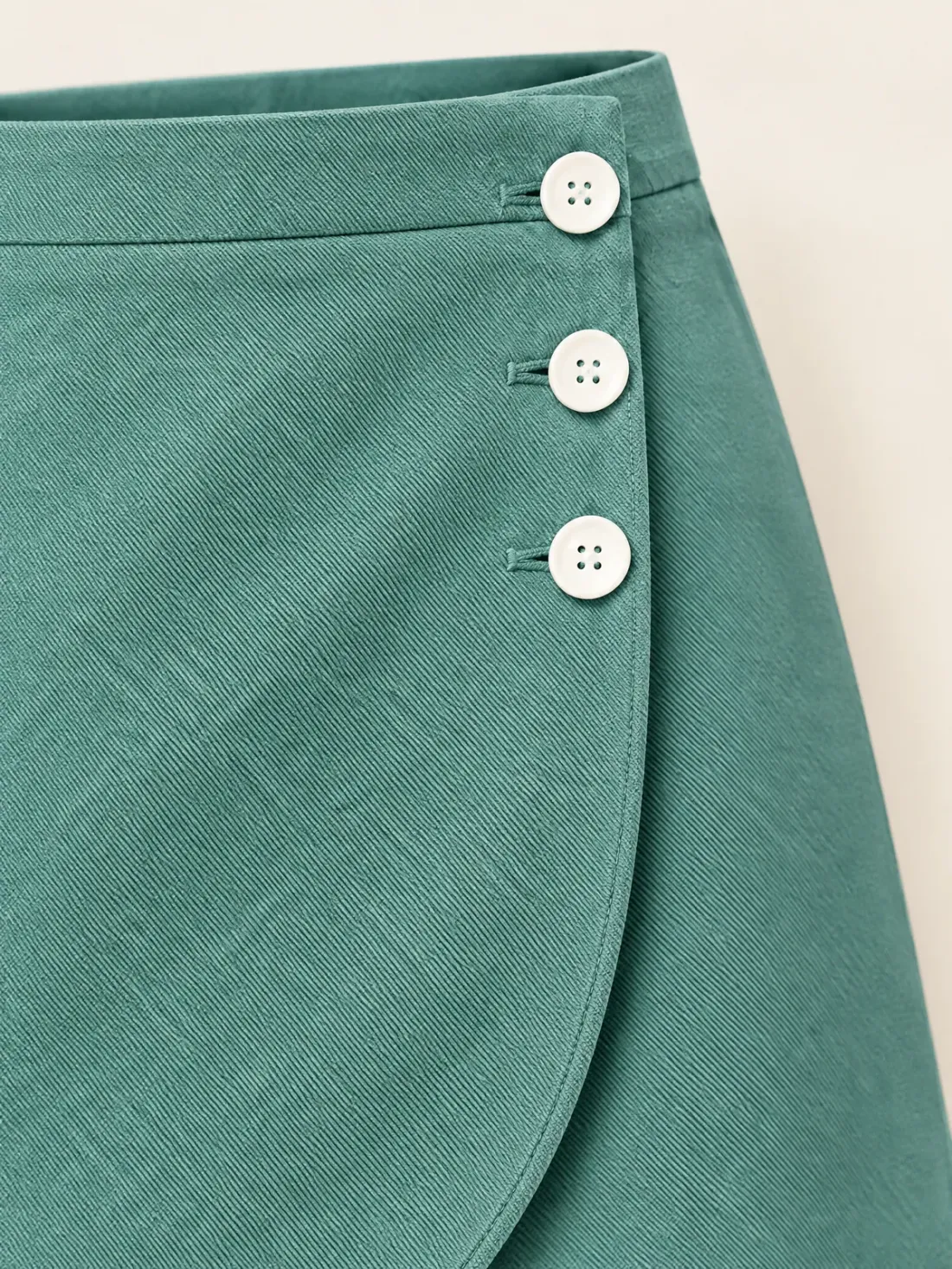 Tidal Wrap Button Mini, close-up of the curved wrap overlap edge with three white buttons
